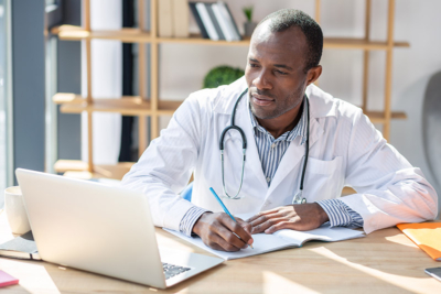 Male physician taking notes from laptop photo